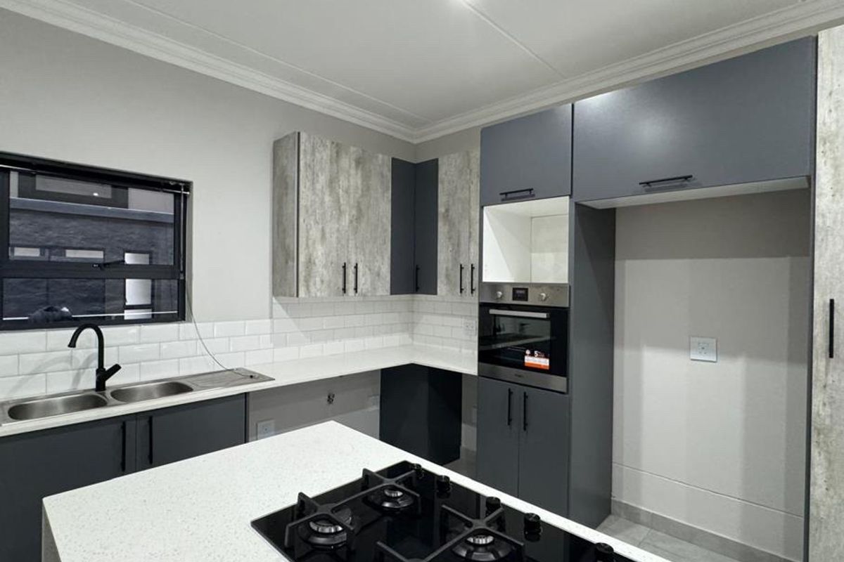 Modern kitchen featuring sleek grey and textured cabinetry, quartz countertops, a built-in oven, gas hob, and a stylish subway tile backsplash.