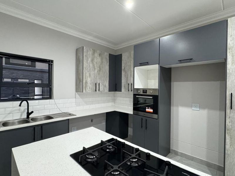 Modern kitchen featuring sleek grey and textured cabinetry, quartz countertops, a built-in oven, gas hob, and a stylish subway tile backsplash.