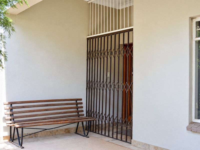 A covered patio area featuring a secure metal gate entrance and tiled flooring, providing a functional and protected entry point to the home.