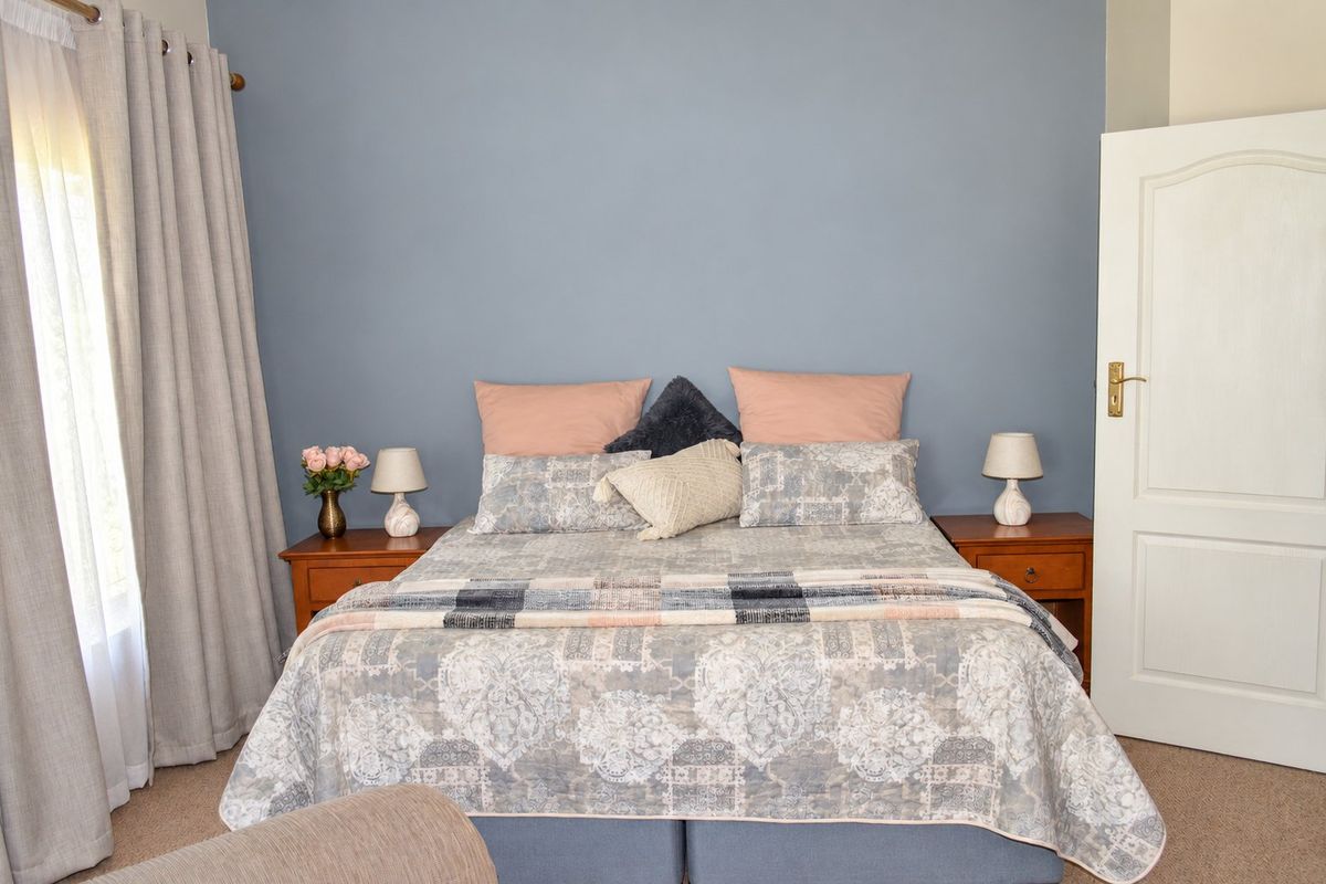 A well-maintained bedroom featuring neutral carpeting, a blue accent wall, and a classic panel door.