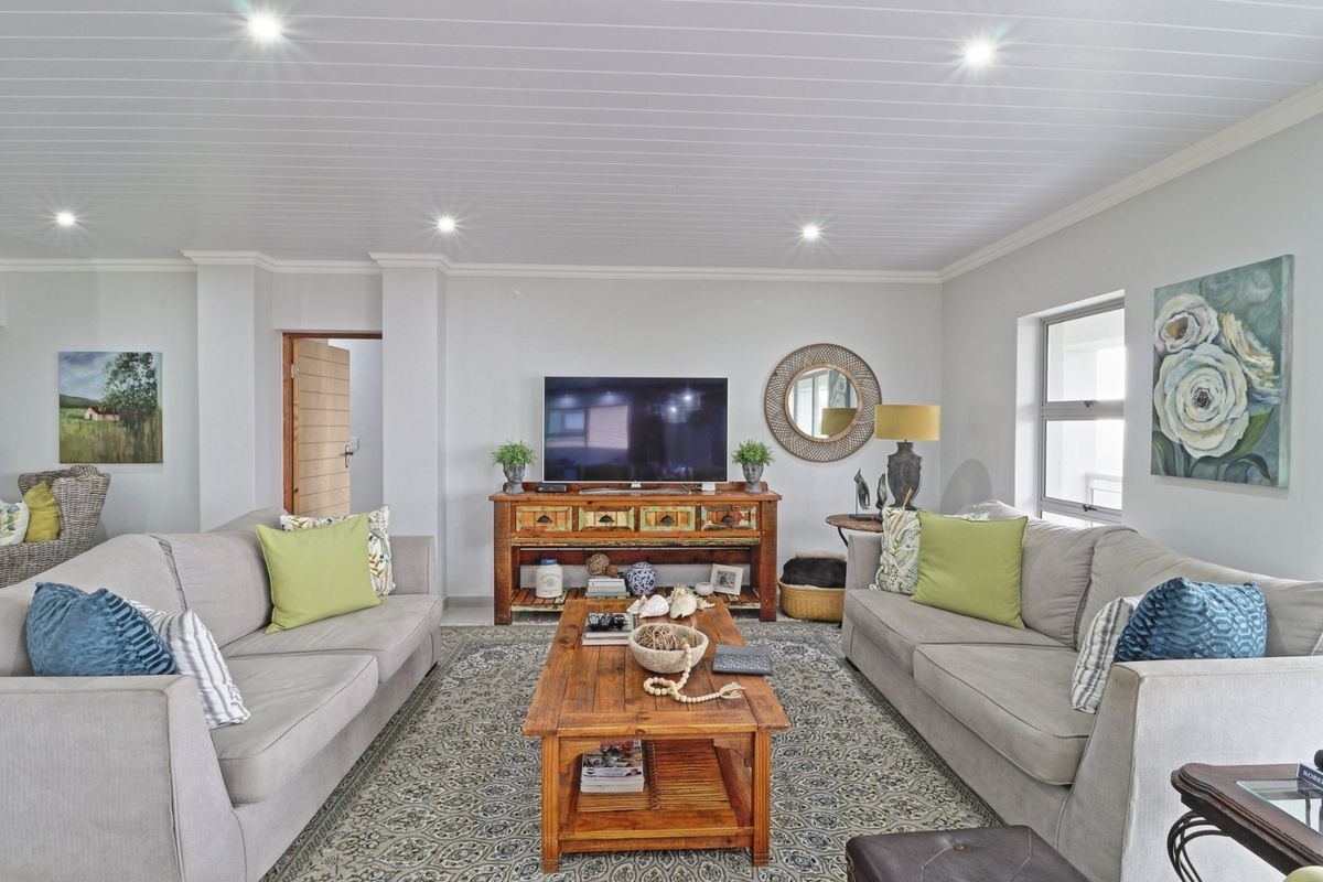 A well-maintained living room featuring a tongue and groove ceiling with recessed downlights and neutral wall finishes.