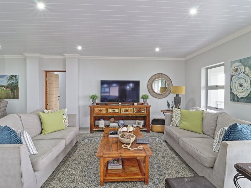 A well-maintained living room featuring a tongue and groove ceiling with recessed downlights and neutral wall finishes.