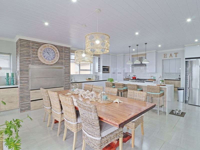Spacious open-plan kitchen and dining area featuring a large island, modern cabinetry, built-in braai, and high-quality finishes throughout.