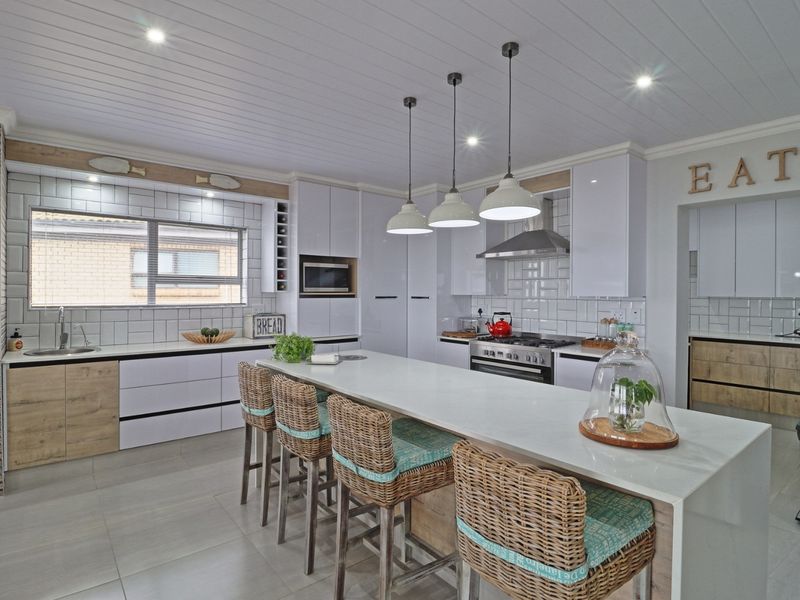 Modern kitchen featuring a large central island with quartz countertops, high-end built-in appliances, subway tile backsplash, and stylish pendant lighting.