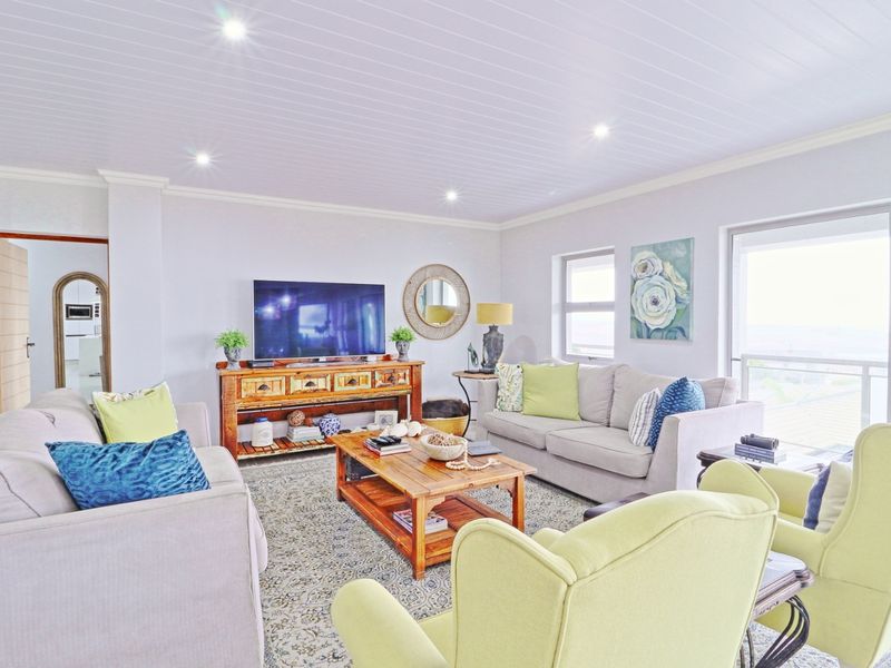 A bright and well-maintained living room featuring a tongue and groove ceiling, recessed downlights, and large sliding glass doors leading to an outdoor area.