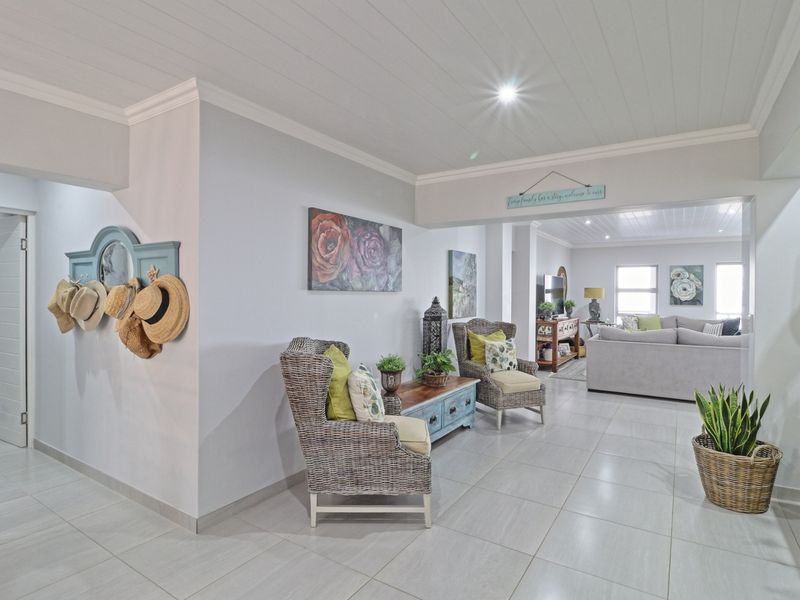 An open-plan living area featuring light-toned tiled flooring, a white tongue and groove ceiling, and recessed lighting, creating a bright and cohesive living space.
