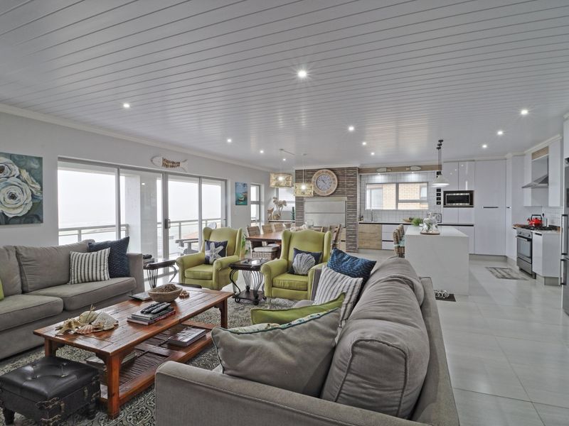 Spacious open-plan living area featuring a modern kitchen with island, tiled floors, recessed lighting, and large sliding doors leading to an outdoor space.