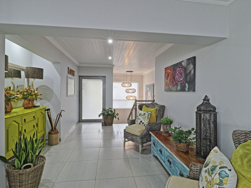 A bright and welcoming entrance hall featuring modern tiled flooring, a stylish tongue and groove ceiling, and recessed lighting.