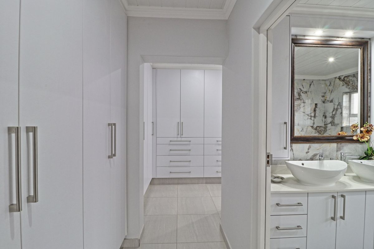 Modern bathroom featuring a double vanity with vessel sinks, stone countertops, and extensive built-in cabinetry for storage, finished with neutral floor tiles.