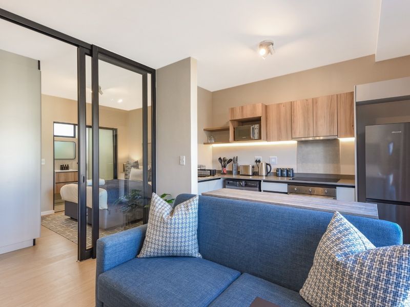Modern open-plan apartment featuring a sleek kitchen with built-in appliances and a stylish sliding glass partition separating the living area from the bedroom.