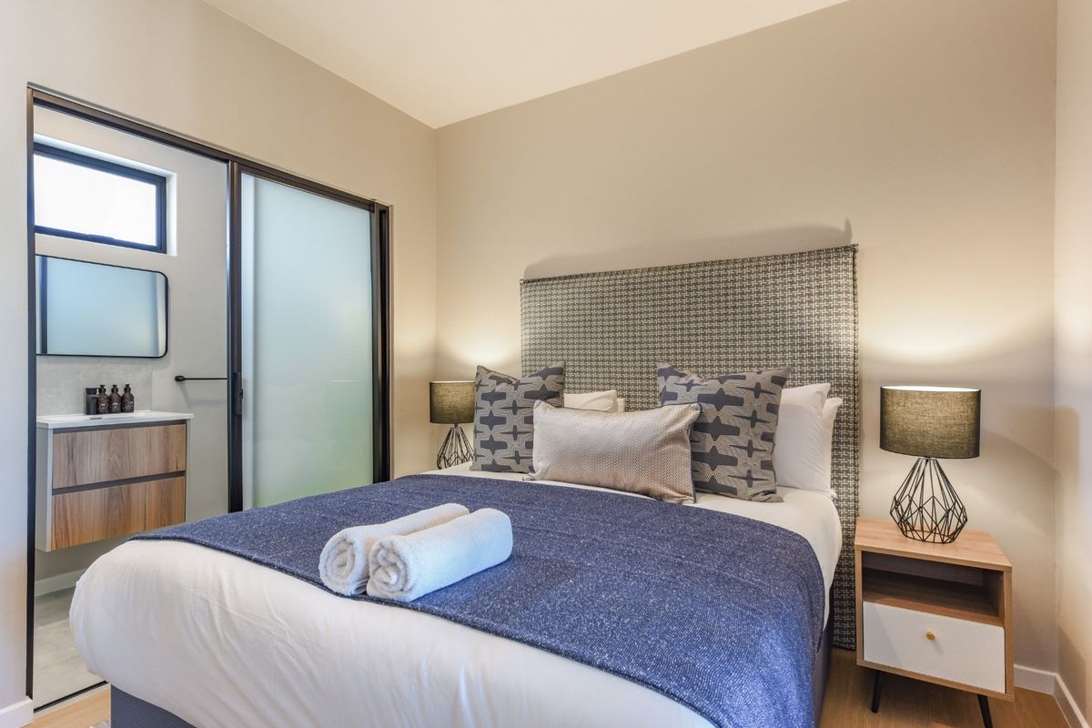 A well-appointed bedroom featuring an integrated en-suite bathroom with a modern vanity and sliding glass door access.
