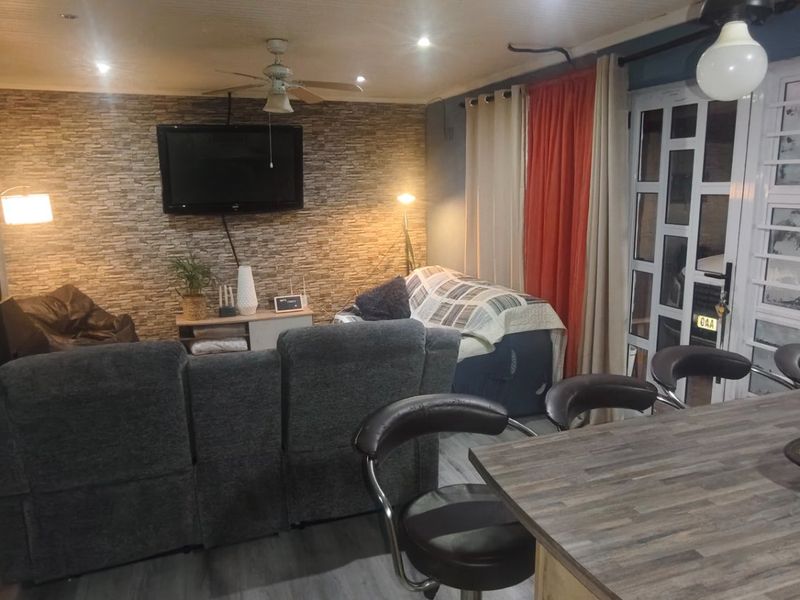 Open-plan living area featuring a stone-cladding accent wall, wood-burning fireplace, and a breakfast bar, creating a cozy and functional multi-purpose space.