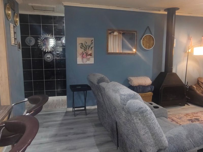 Open plan living area featuring a modern freestanding fireplace, stone veneer accent wall, and durable laminate flooring, creating a cozy and functional space.