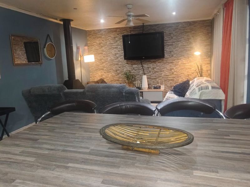 Open-plan living area featuring a stone-cladding accent wall, wood-burning fireplace, and direct access to the exterior through sliding glass doors.