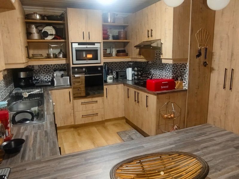 A functional kitchen featuring light wood-tone cabinetry, patterned tile backsplash, laminate countertops, and integrated appliances including an oven and microwave.