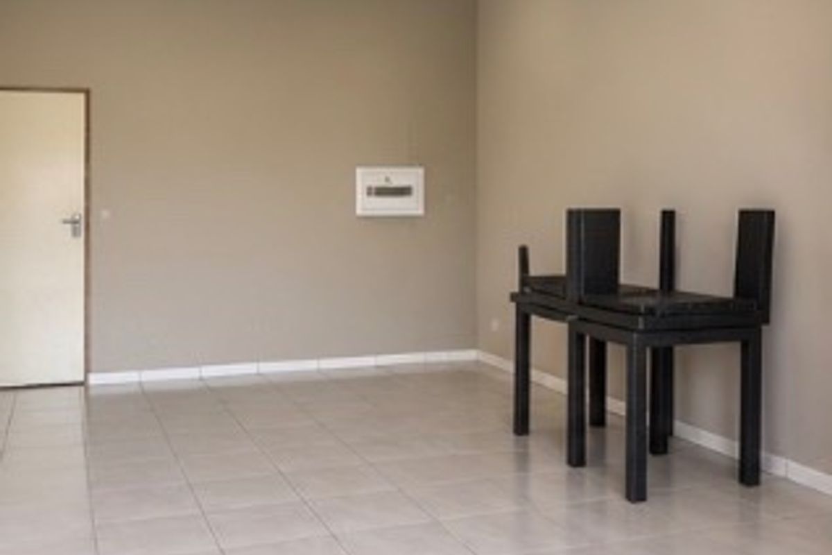 A clean, vacant office space featuring neutral wall tones, tiled flooring, and recessed downlighting, suitable for various commercial business applications.