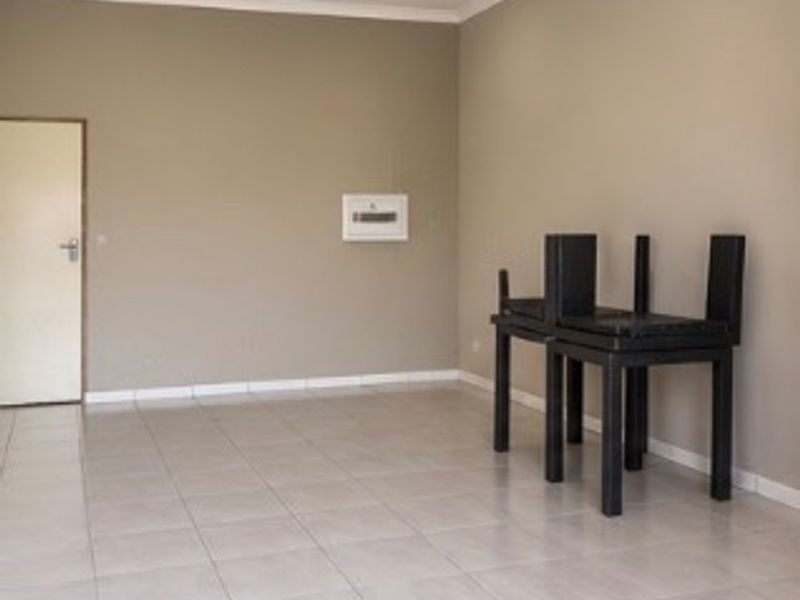 A clean, vacant office space featuring neutral wall tones, tiled flooring, and recessed downlighting, suitable for various commercial business applications.