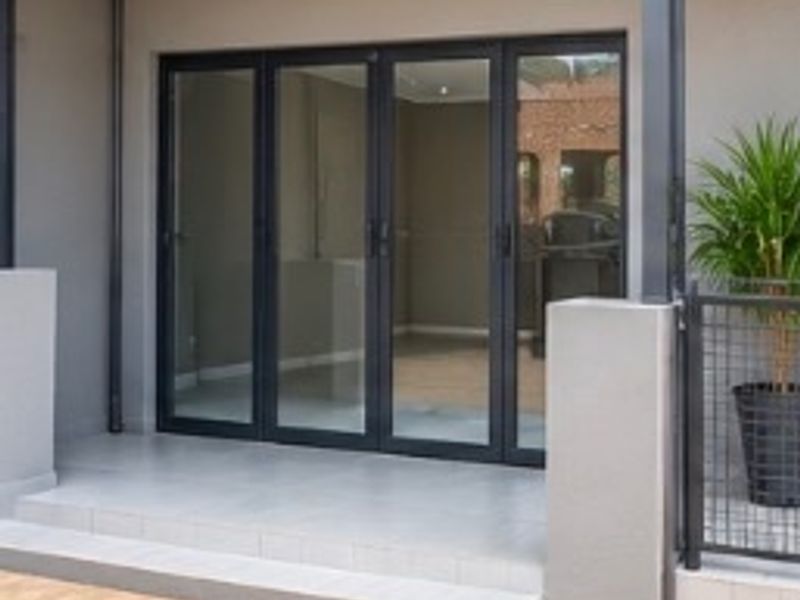 A modern covered patio area featuring tiled flooring, aluminium sliding doors, and recessed lighting, providing a clean transition to the interior space.