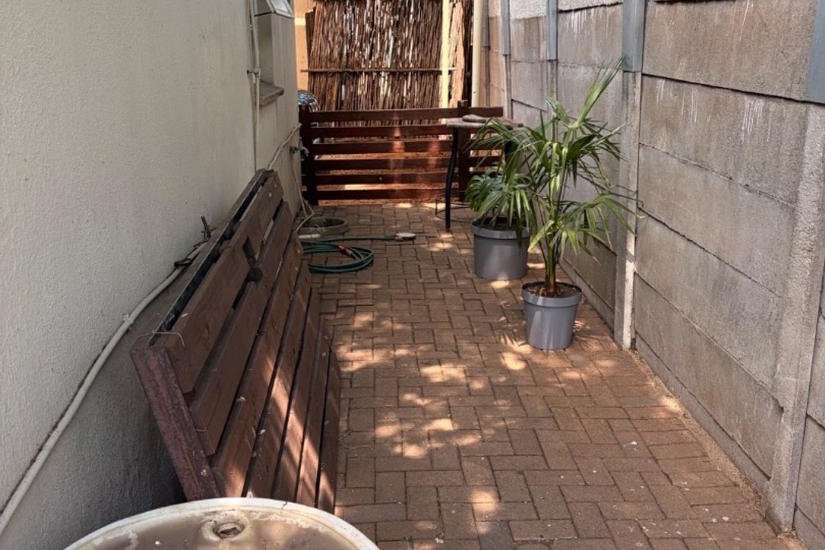 A narrow rear exterior walkway featuring paved flooring and a precast concrete boundary wall, offering potential for landscaping or outdoor storage improvement.