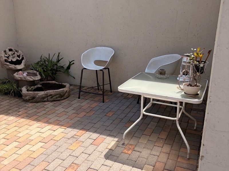 A private outdoor patio area featuring durable brick paving and a wall-mounted light fixture, providing a functional space for outdoor relaxation.