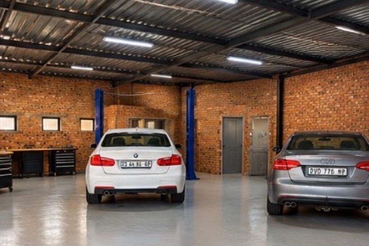 Spacious commercial garage featuring exposed brick walls, high-clearance corrugated metal ceiling, durable epoxy flooring, and integrated vehicle service lifts.