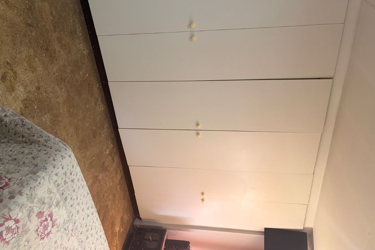 A bedroom featuring floor-to-ceiling built-in cupboards and worn carpeting, requiring updates to flooring and finishes to improve the overall aesthetic.