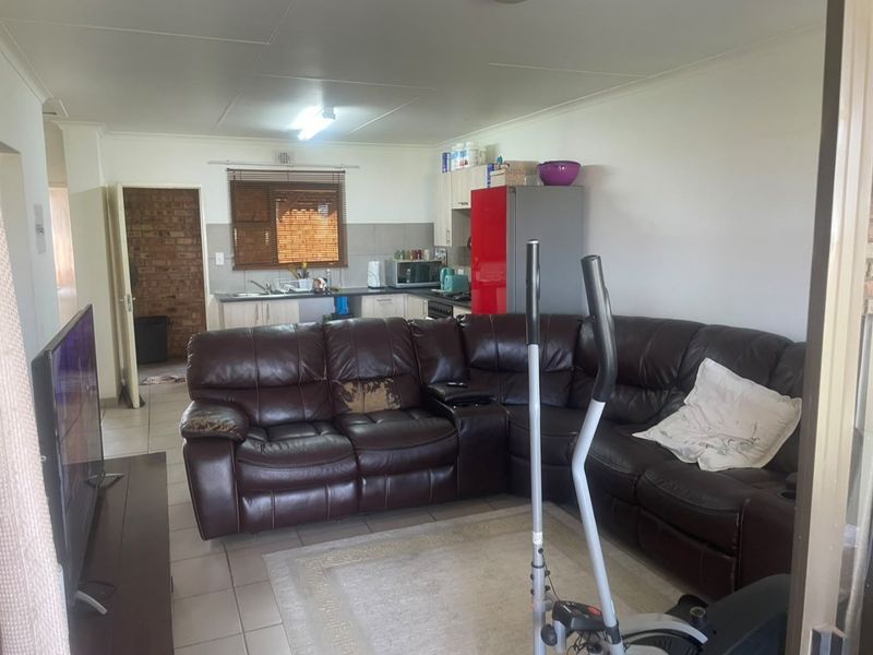 Open plan living area featuring a functional kitchen with cabinetry and tiled flooring, seamlessly connected to the main living space.