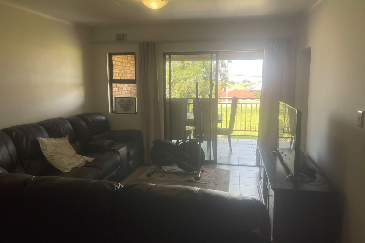 A living room featuring tiled flooring and a sliding glass door providing access to an outdoor balcony area.