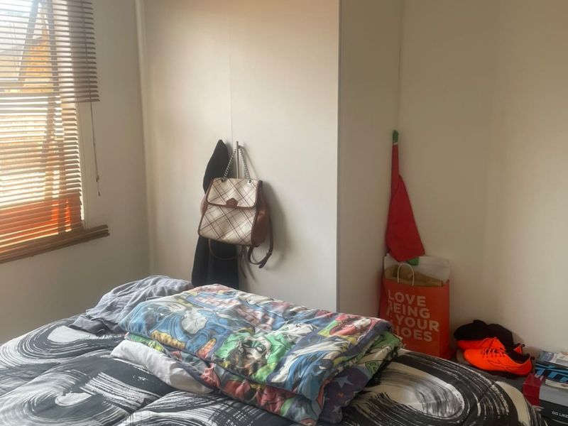 A bedroom featuring a built-in wardrobe and venetian blinds on the window.