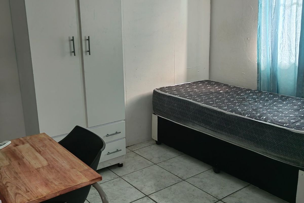A functional bedroom featuring tiled flooring and a built-in wardrobe, offering a simple layout ready for personalization.