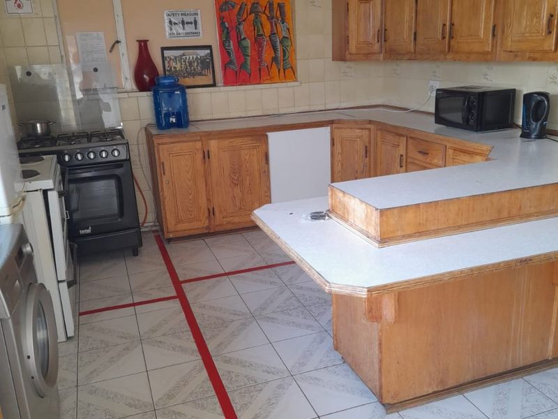 A functional kitchen featuring wooden cabinetry, laminate countertops, tiled flooring, and a built-in gas stove with oven.