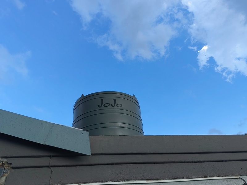 A view of a green JoJo water storage tank installed on the roof of the property.