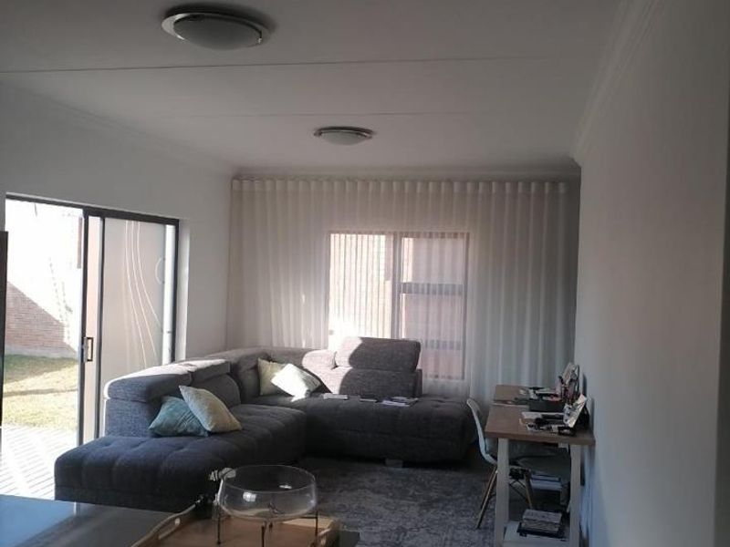 An open-plan living area featuring tiled flooring, recessed lighting, and a sliding glass door providing access to the outdoor space.