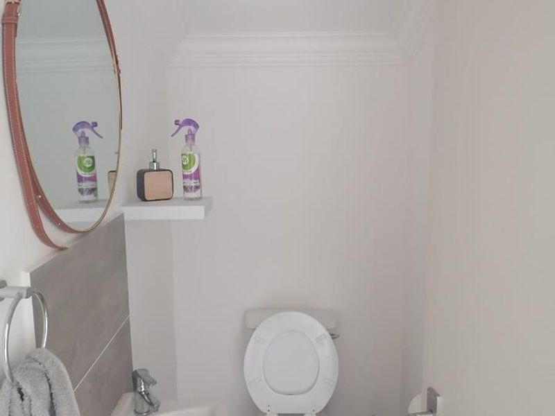 A compact guest bathroom featuring a wall-mounted basin, modern chrome faucet, tiled splashback, and a standard toilet.