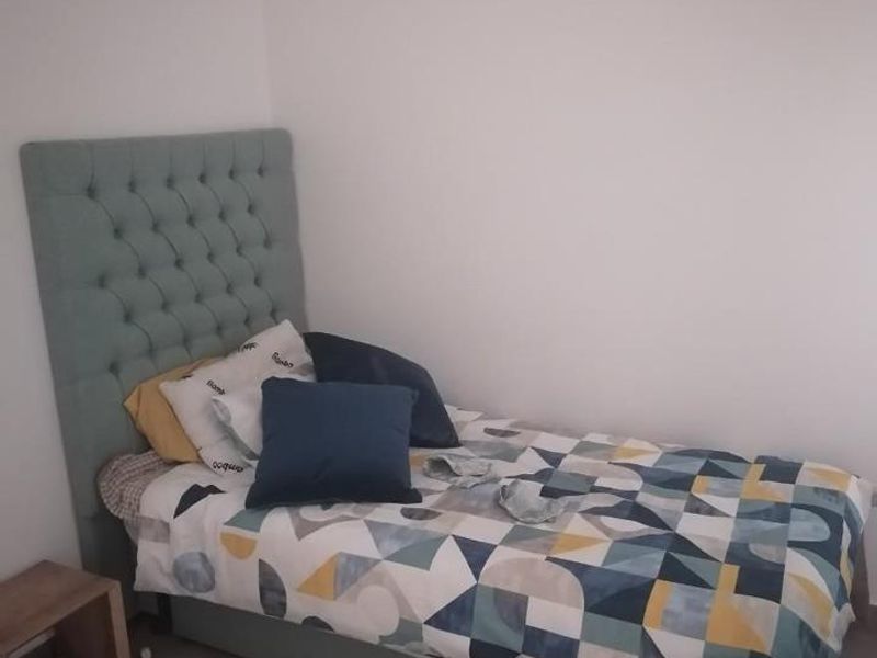 A simple bedroom featuring neutral wall finishes and wood-look flooring.