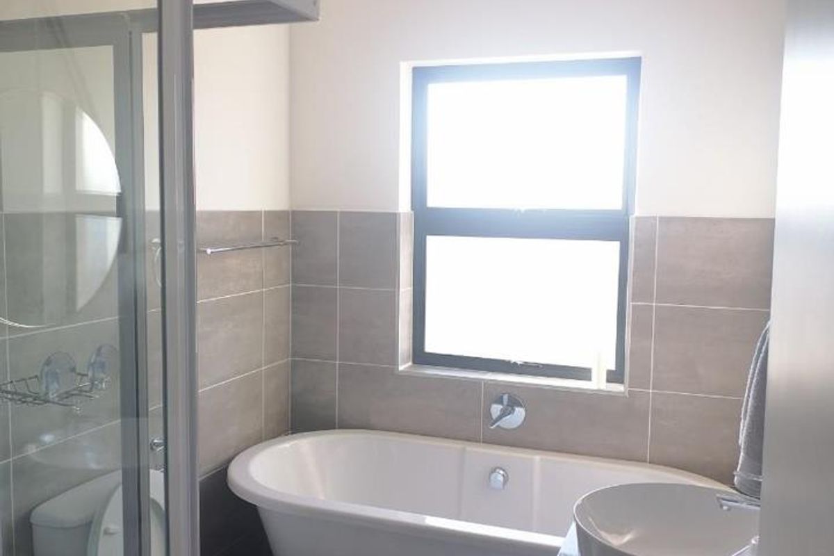 A modern bathroom featuring a freestanding bathtub, a glass-enclosed shower, and a contemporary vessel sink set on a vanity cabinet.