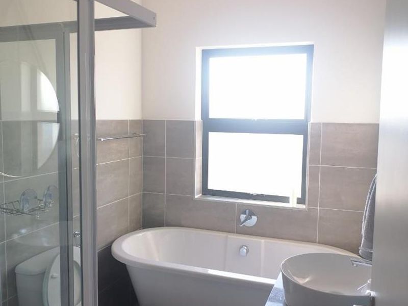 A modern bathroom featuring a freestanding bathtub, a glass-enclosed shower, and a contemporary vessel sink set on a vanity cabinet.