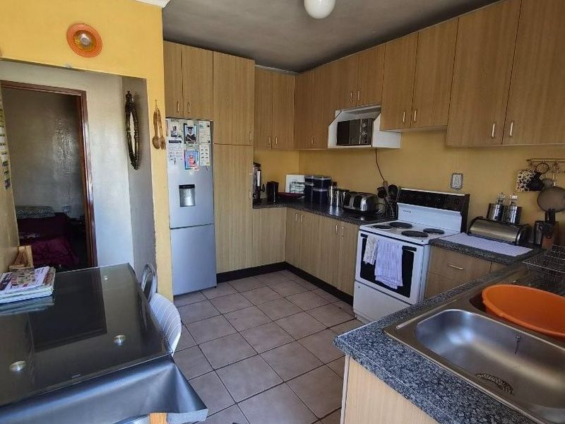 Functional kitchen featuring laminate cabinetry, granite countertops, and tiled flooring, offering a practical layout with integrated stove and extractor fan.