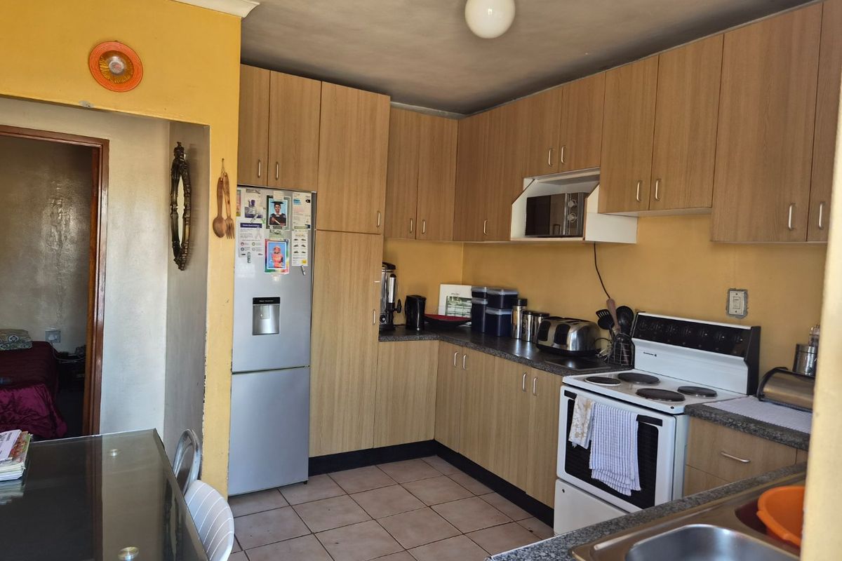 A functional kitchen featuring laminate cabinetry, stone-look countertops, and a freestanding electric stove, offering potential for modernization and aesthetic updates.
