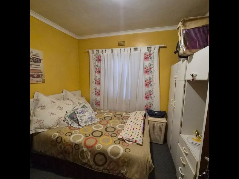 A functional bedroom featuring a built-in wardrobe, coving, and an air vent, providing a practical space for rest.