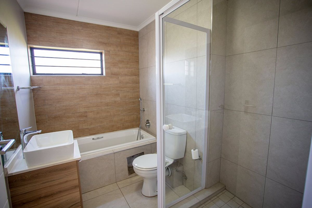 Modern bathroom featuring a built-in vanity with vessel sink, a separate bathtub, and a glass-enclosed shower with neutral floor-to-ceiling tiling.