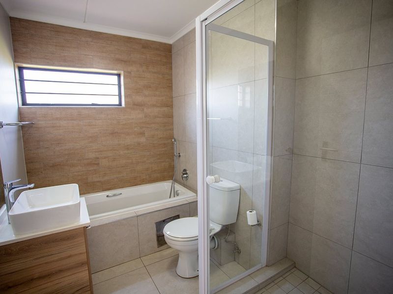 Modern bathroom featuring a built-in vanity with vessel sink, a separate bathtub, and a glass-enclosed shower with neutral floor-to-ceiling tiling.