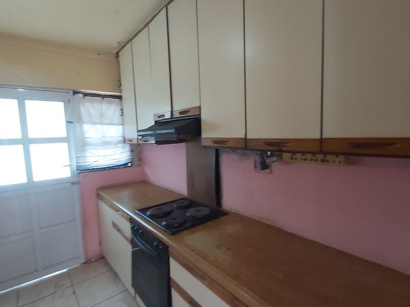 A dated kitchen featuring built-in cabinetry, an electric hob, and an oven, requiring cosmetic updates to modernize the space.