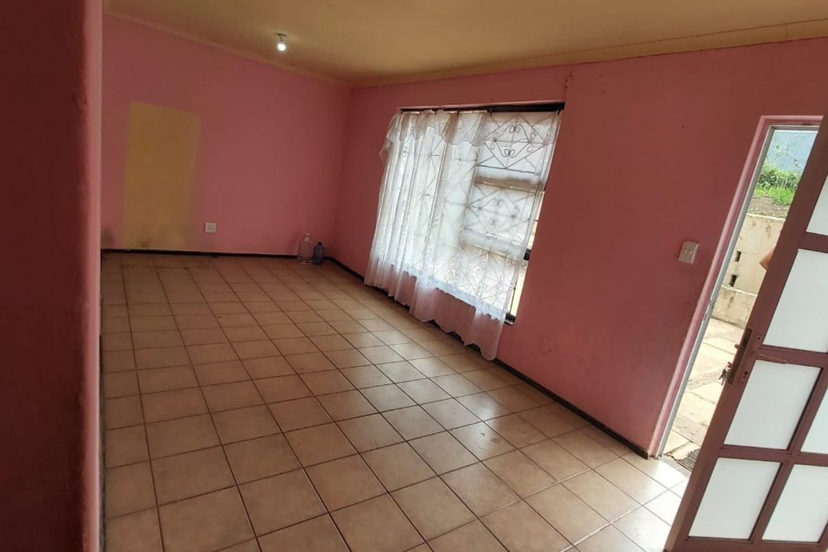An empty living room featuring ceramic tiled flooring, pink walls, and a glass panel door leading to the exterior.
