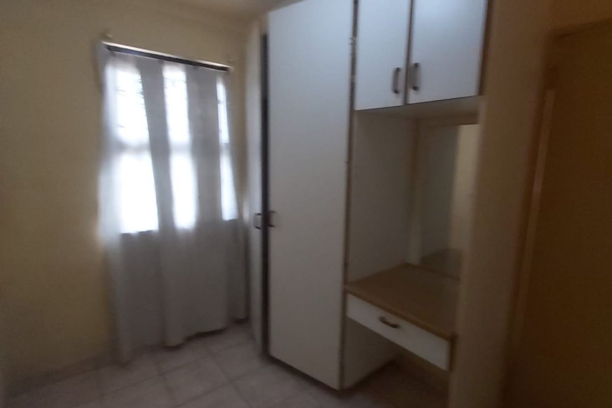 A simple bedroom featuring built-in cabinetry with an integrated vanity and tiled flooring.
