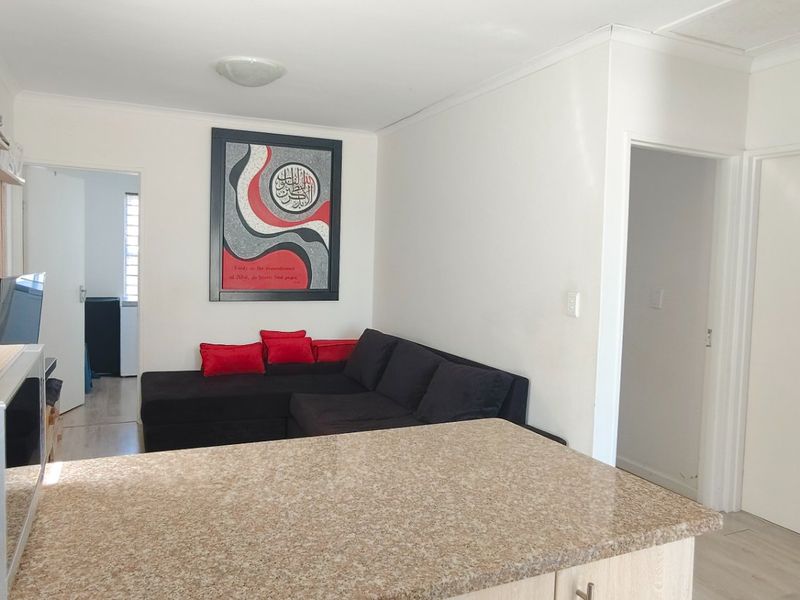 Open plan living area featuring a granite-topped kitchen counter and laminate flooring, connecting to adjacent rooms.