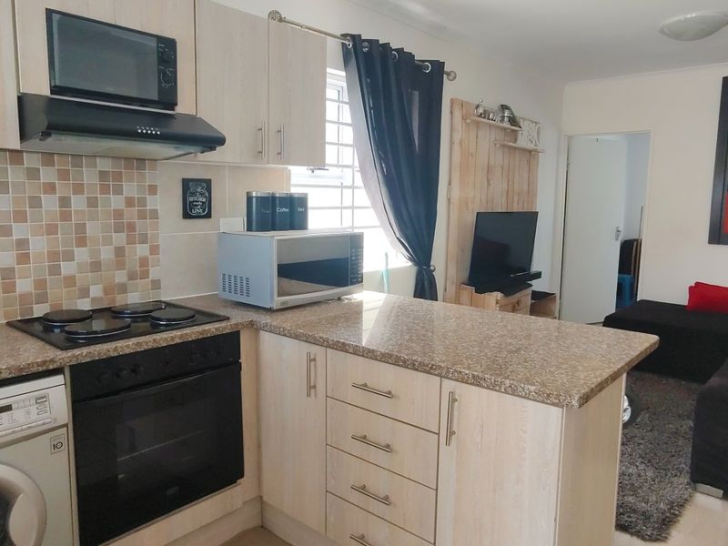 Open-plan kitchen and living area featuring light wood cabinetry, granite countertops, integrated appliances, and a functional breakfast nook layout.