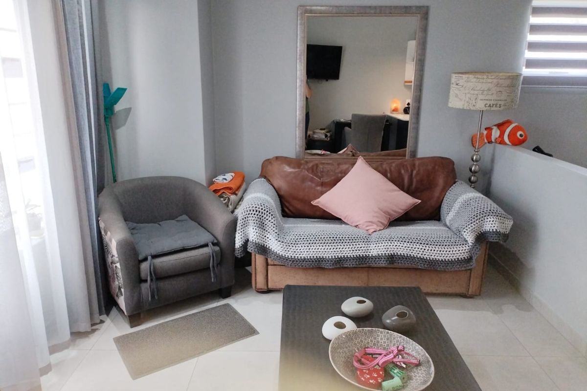 A living room area featuring neutral tiled flooring and modern roller blinds, providing a functional and well-lit space.