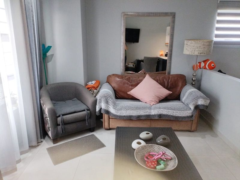 A living room area featuring neutral tiled flooring and modern roller blinds, providing a functional and well-lit space.