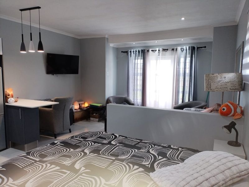 An open-plan living area featuring a breakfast bar, recessed ceiling lighting, and a partition wall separating the sleeping area from the living space.